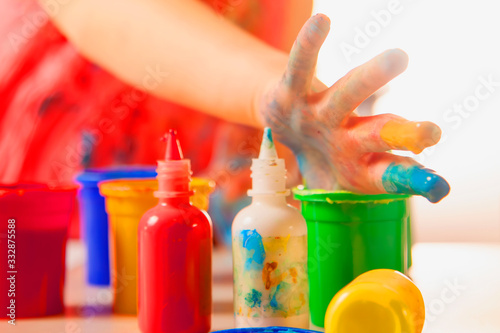 Cute little child girl learn to painting with finger. Selective focus on finger in paints.