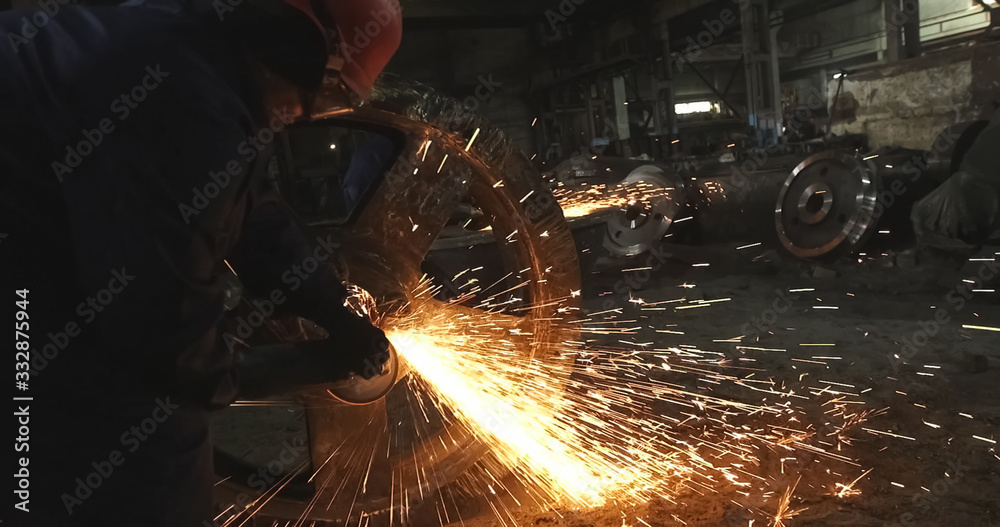 Working in a mask and headphones cleans joints angle grinder on metal parts blanks Working in a mask and headphones cleans joints angle grinder on metal parts blanks