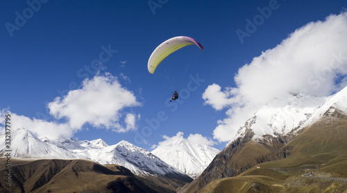 Hang glider in high mountains in Georgia - with some clouds on it and snow.