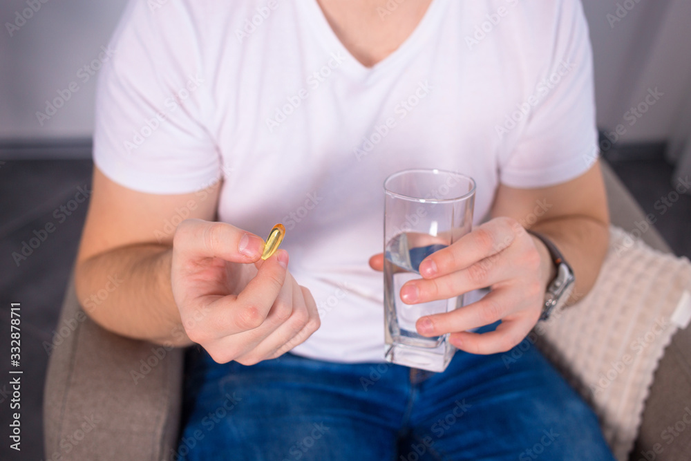 Man taking his pills on couch in the living room Man taking his pills on couch in the living room