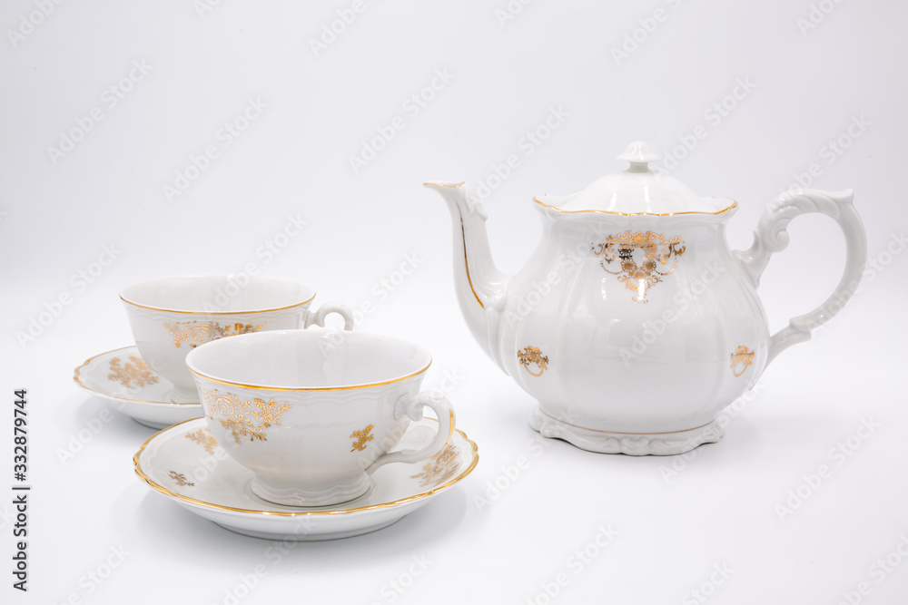 Vintage white teapot with tea cups with golden design in classic style isolated on white background