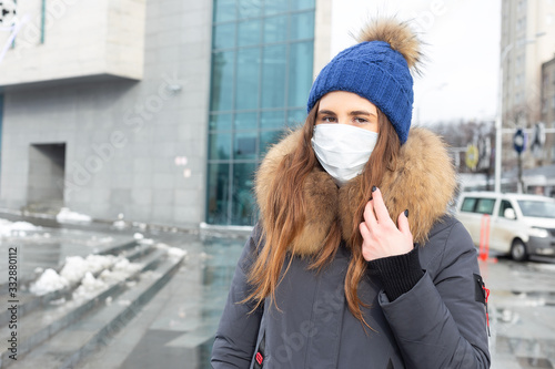 Portrait of woman walking down the street in winter in a protective mask to protect against infectious diseases. Protection against colds, flu, air pollution. Health concept © simikov