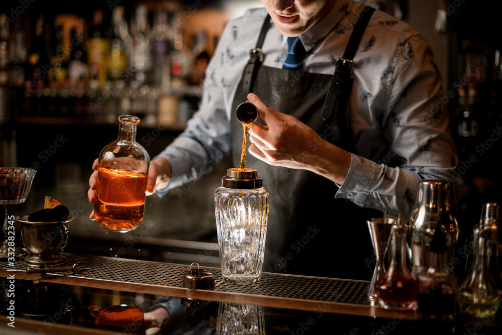 bartender using beaker pours drink into glass shaker