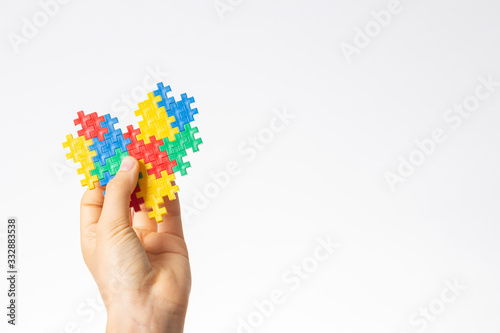 World autism awareness day concept. Child hands holding colorful puzzle heart on white background