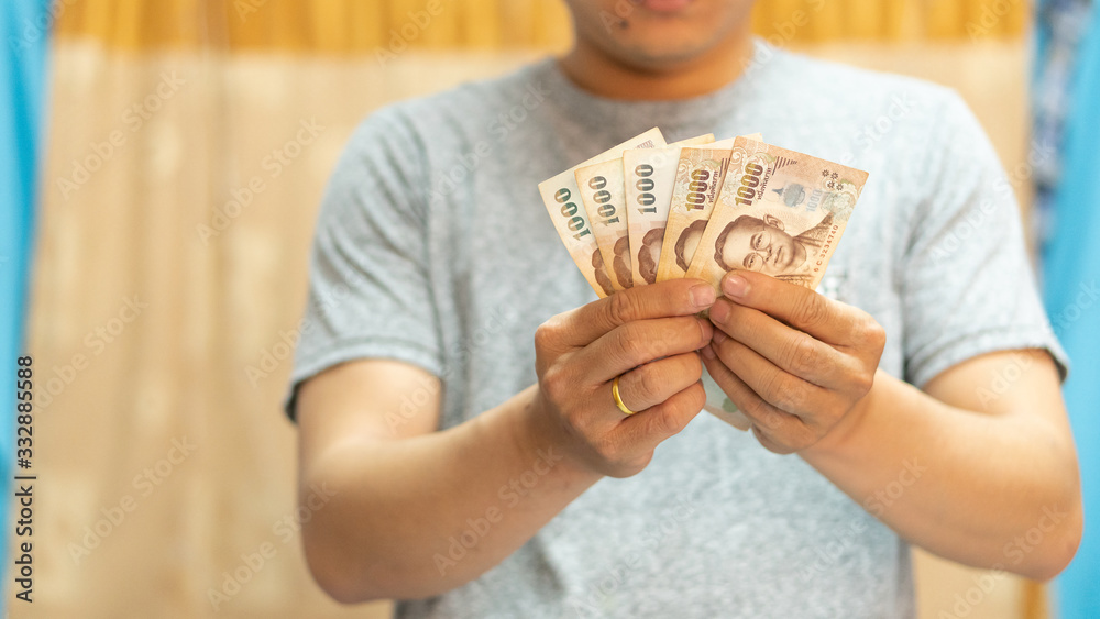 A man with a Thai government 5000 baht in hand