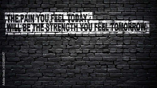 the pain you feel today, will be the strength you feel tomorrow, motivation and inspiration slogan, white text on black brick wall