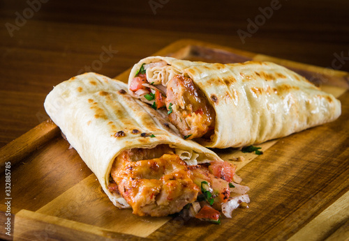 Shawarma pita bread with grilled chicken, shaurma doner, fresh vegetables and cream sauce on a light stone or concrete background. Top view with copy space, concept restaurant fast food