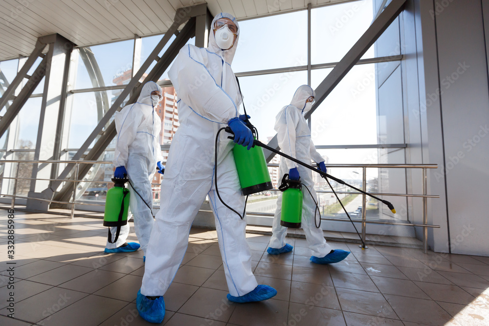 Men in respirators and protective suits cleaning public places with chemicals - obrazy, fototapety, plakaty 