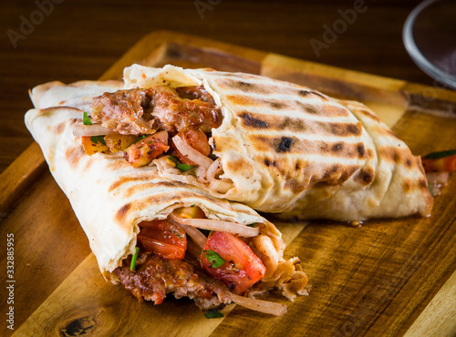 Shawarma pita bread with grilled chicken, shaurma doner, fresh vegetables and cream sauce on a light stone or concrete background. Top view with copy space, concept restaurant fast food