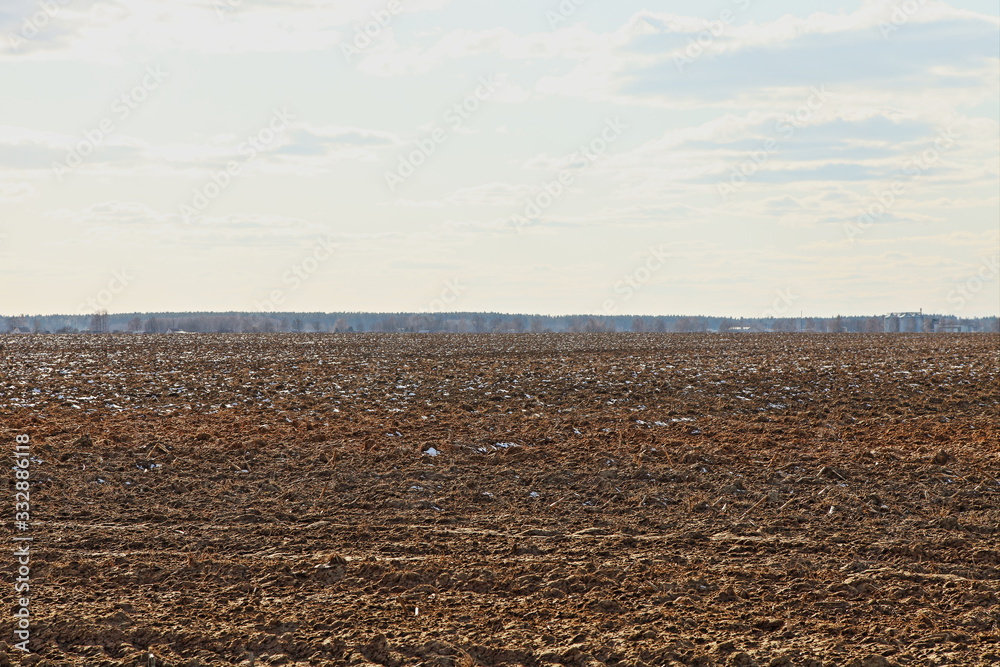 A vast brown ploughed field against a blue sky on a spring day — land cultivation, agriculture, rural landscape A vast brown ploughed field against a blue sky on a spring day — land cultivation, agriculture, rural landscape