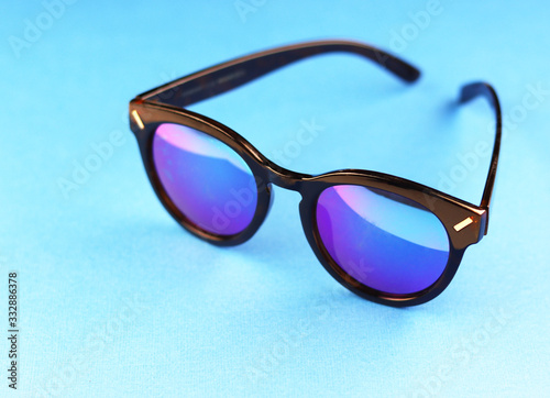summer sunglasses on a blue background. glasses with black bezel and mother-of-pearl lenses
