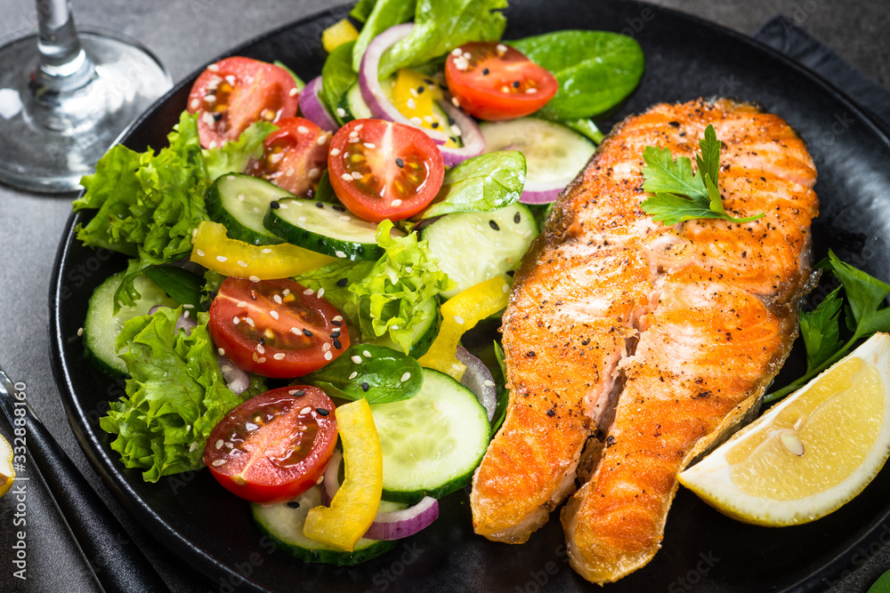 Grilled salmon fish steak with vegetables on black. Grilled salmon fish steak with vegetables on black.