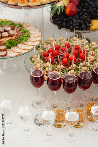 Close up of large selection of food with cold snacks, alcohol, wine glasses, cold meats, cheese. Variety of tasty delicious snacks on the table. Corporate birthday party event or wedding celebration