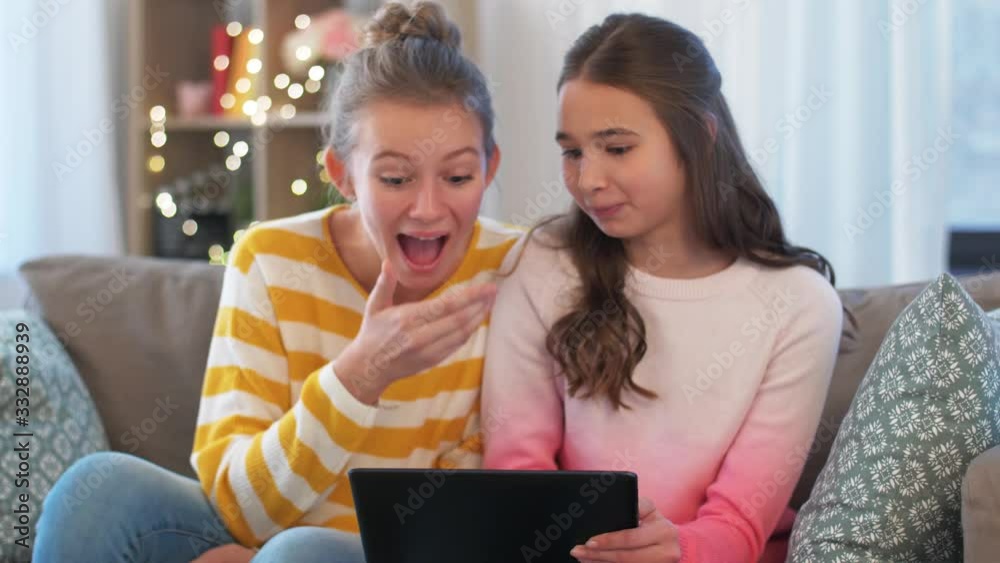 people, technology and friendship concept - happy teenage girls with tablet computer sitting on sofa at home people, technology and friendship concept - happy teenage girls with tablet computer sitting on sofa at home