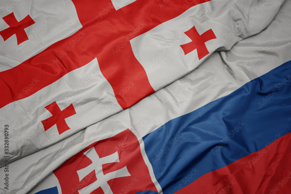 Fototapeta premium waving colorful flag of slovakia and national flag of georgia.