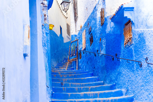 Easel with a picture on the street with stairway in Chefchaouen, blue town Morocco. © ggfoto