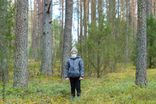 Disappointed lonely kid wearing mask for protection of corona virus spread on a empty forest. © Augustas Cetkauskas