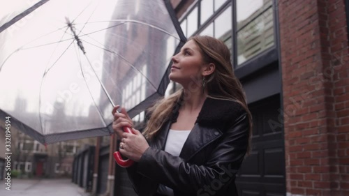 A beautiful young woman enjoys a stroll through the city on a rainy day with an umbrella