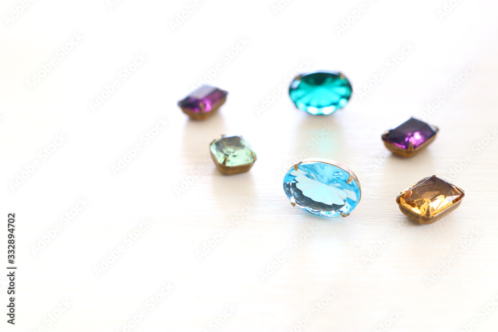 Beautiful crystal clear jems over white wooden background Beautiful crystal clear jems over white wooden background