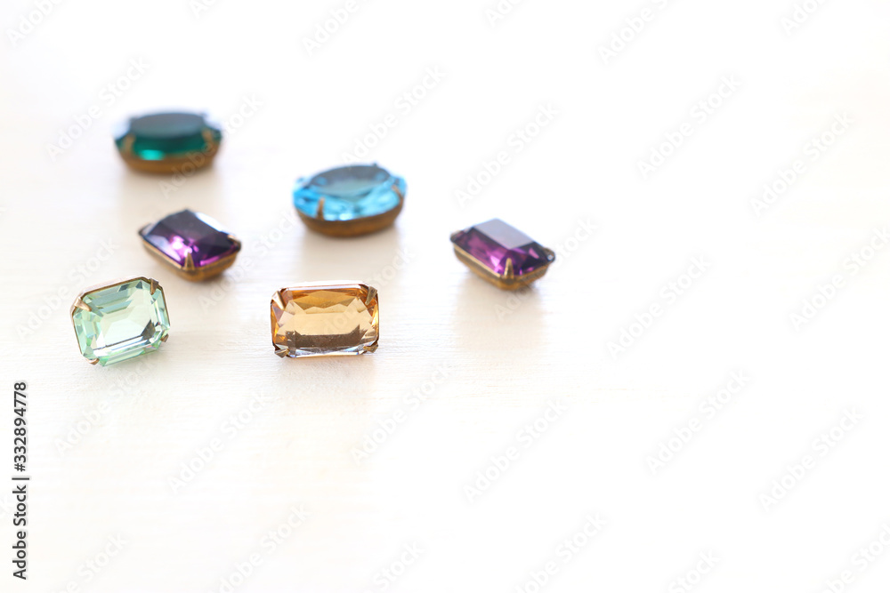 Beautiful crystal clear jems over white wooden background Beautiful crystal clear jems over white wooden background