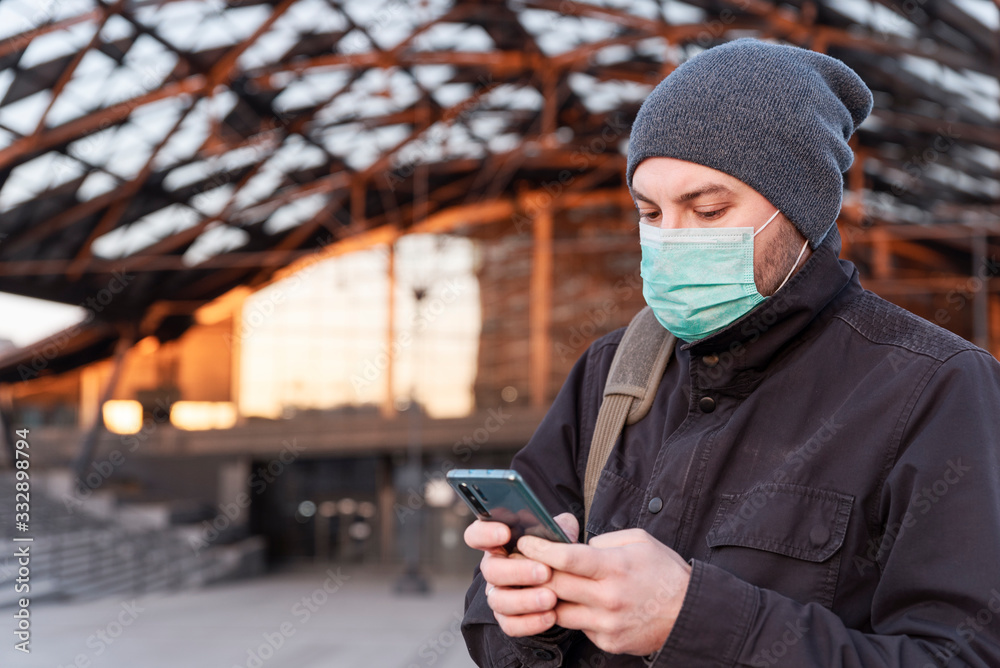 Person in face mask using phone while coronavirus outdoor in the city. Business during pandemic stay safety and health protection. Public transport at station and airport. Person in face mask using phone while coronavirus outdoor in the city. Business during pandemic stay safety and health protection. Public transport at station and airport.