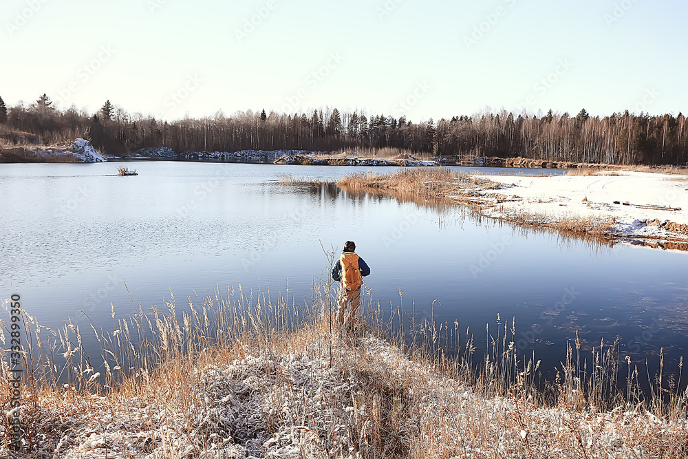 traveler with a backpack by the river / tourist guy on a northern hike, winter trip
