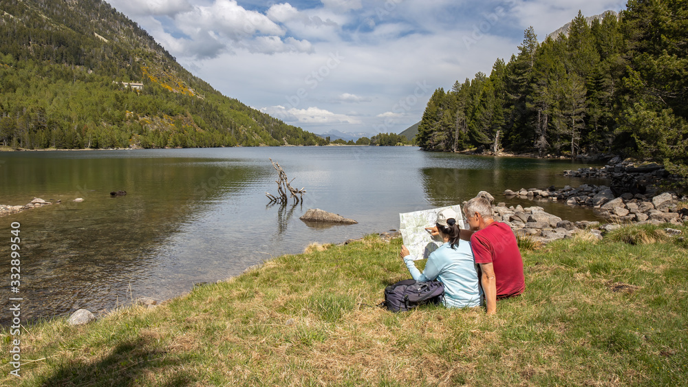 Beautiful Pyrenees mountain landscape, nice lake with tourist couple looking a map. Spain, Catalonia. Beautiful Pyrenees mountain landscape, nice lake with tourist couple looking a map. Spain, Catalonia.