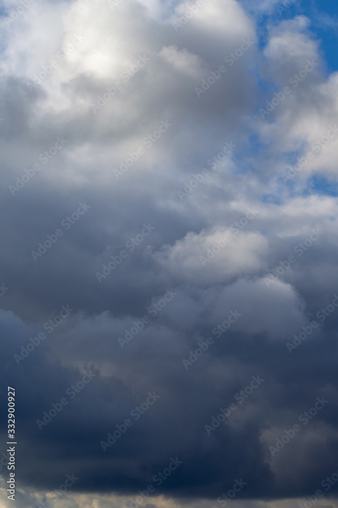 Vertical. Thunderclouds clouds on blue sky. Grey white clouds. Spring day. Beautiful nature background. Vertical. Thunderclouds clouds on blue sky. Grey white clouds. Spring day. Beautiful nature background.