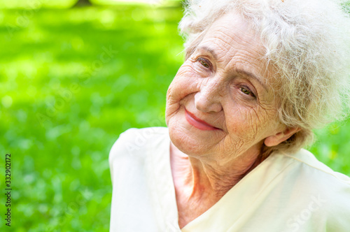 Pretty happy elderly woman on a background of spring greenery close-up with a smile on her face. The health of old people. Retirement Care photo