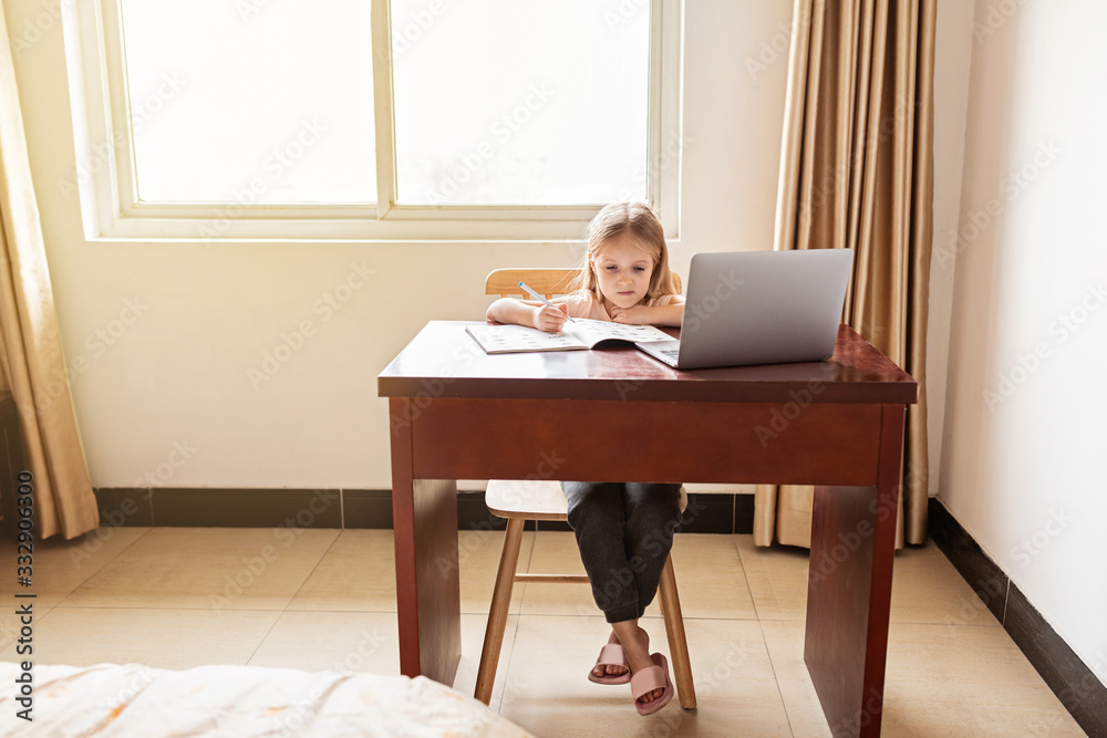 Pretty schoolgirl studying homework during her online lesson at home, social distance during quarantine covid-19, self-isolation, online education concept, home schooler. Workplace in living room. Pretty schoolgirl studying homework during her online lesson at home, social distance during quarantine covid-19, self-isolation, online education concept, home schooler. Workplace in living room.