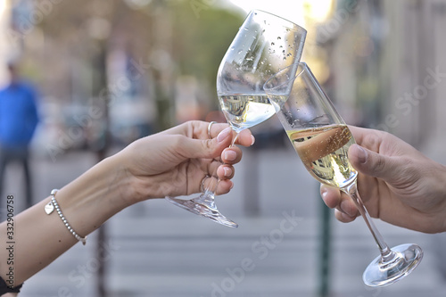 glasses of toast chin chin, hands with glasses of white wine in a street cafe