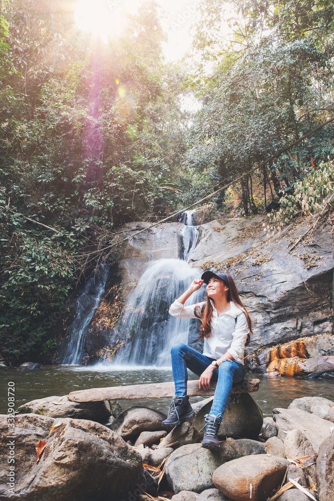 A beautiful asian woman sitting in front of waterfall in the jungle