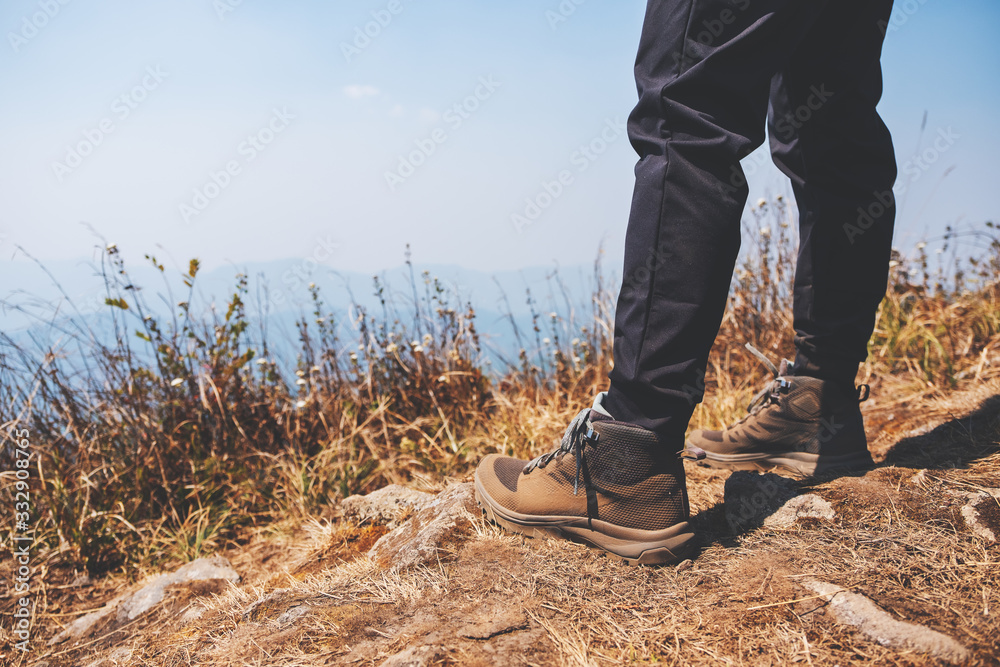 Closeup image of a woman's legs with trekking boots on the top of mountain Closeup image of a woman's legs with trekking boots on the top of mountain
