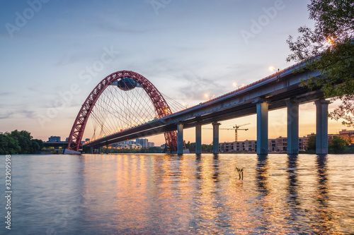 Fototapeta Naklejka Na Ścianę i Meble -  Sunset view of Picturesque bridge with big red arch over the Moscow river, Moscow, Russian Federation.