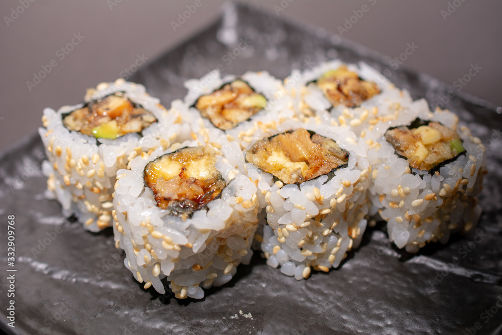 Set of six sushi on a black plate and on a black background