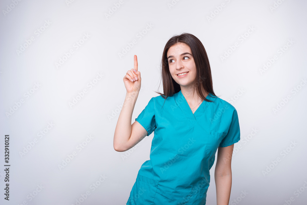 Photo of charming young doctor woman pointing up at copyspace, space for text or product Photo of charming young doctor woman pointing up at copyspace, space for text or product