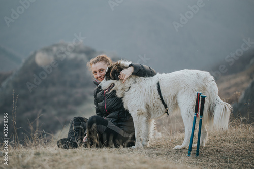 Fototapeta Naklejka Na Ścianę i Meble -  Young woman tourist hugging her dog outdoors while hiking with her best friend. 
