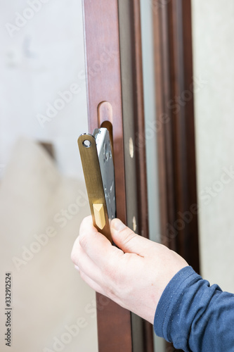master repairing a door lock in a room, man, Close-up of a door repair, professional locksmith installing or repairing a new gateway on a house, closeup hands tighten a lock
