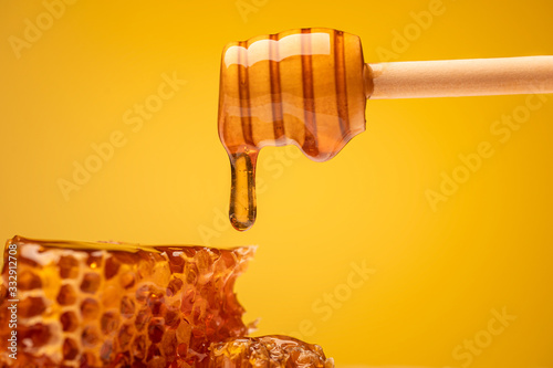 dripping sweet honey from wooden dipper and honeycomb