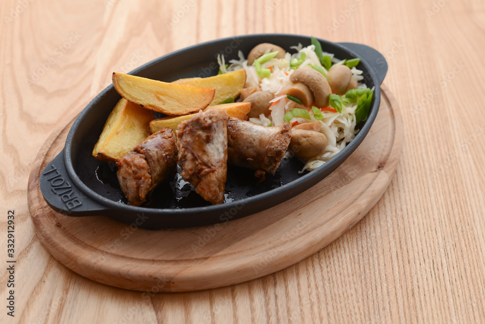 Grilled meat in mushroom's sauce and baked potato with cabbage mushroom salad in a pan on rustic wooden table. Grilled meat in mushroom's sauce and baked potato with cabbage mushroom salad in a pan on rustic wooden table.