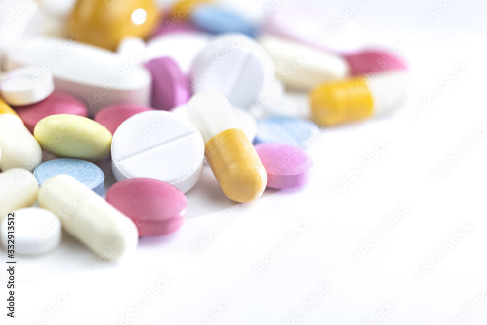 Multi-colored pills are scattered on the table. Pills of different sizes and purposes, small, large, white, pink, blue, yellow. For various illnesses, tablets lie as a backdrop with copy space. Multi-colored pills are scattered on the table. Pills of different sizes and purposes, small, large, white, pink, blue, yellow. For various illnesses, tablets lie as a backdrop with copy space.