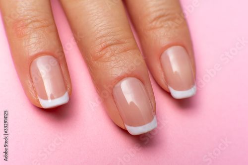 three female fingers with a beautiful manicure on a pink background.