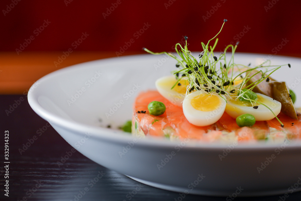 Smoked salted salmon served with boiled quail eggs and herbs, lemon and green peas on a white plate Smoked salted salmon served with boiled quail eggs and herbs, lemon and green peas on a white plate