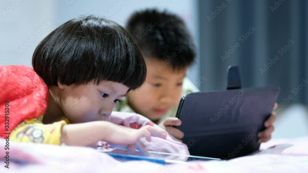 two chinese children addicted tablet, asian child watching tablet, kid use telephone together on their bed, play phone, kid addict smartphone two chinese children addicted tablet, asian child watching tablet, kid use telephone together on their bed, play phone, kid addict smartphone