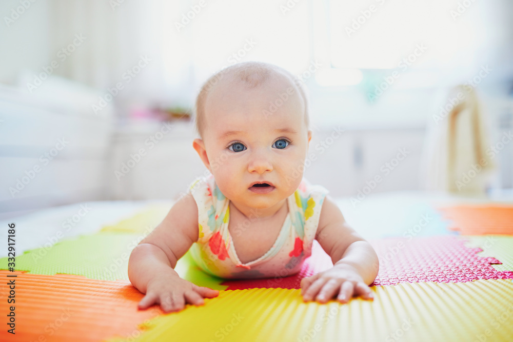 baby girl lying on colorful play mat on the floor baby girl lying on colorful play mat on the floor