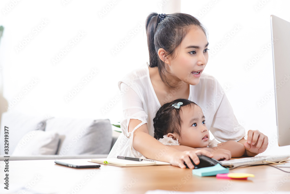Asian mother watching her daughter who is learning to use the computer. Mom and kids, education, family relationship, child care, technology for children concept. Asian mother watching her daughter who is learning to use the computer. Mom and kids, education, family relationship, child care, technology for children concept.