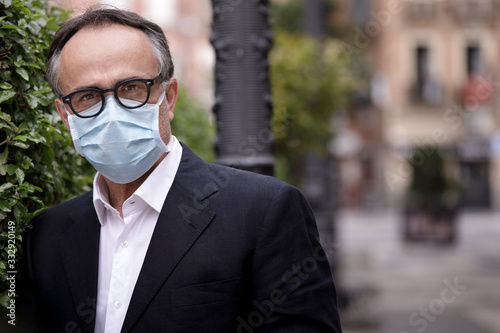 Ritratto di manager di mezza eta con una mascherina protettiva per evitare il contagio, sfondocontesto urbano