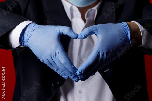 cuore formato dalle mani che indossano dei guanti in lattice sullo sfondo  il busto di una persona photo