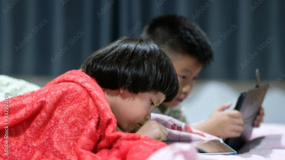 two chinese children addicted tablet, asian child watching tablet, kid use telephone together on their bed, play phone, kid addict smartphone two chinese children addicted tablet, asian child watching tablet, kid use telephone together on their bed, play phone, kid addict smartphone