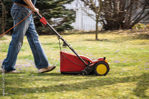 Gardener verticutting the lawn at spring. Panning shot of verticutter, motion blur photo